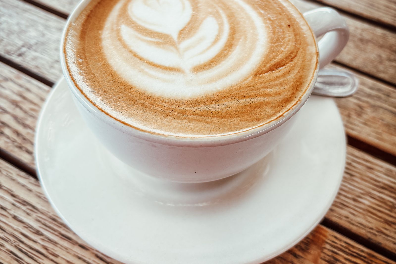 Kop cappuccino med latte art på et træbord