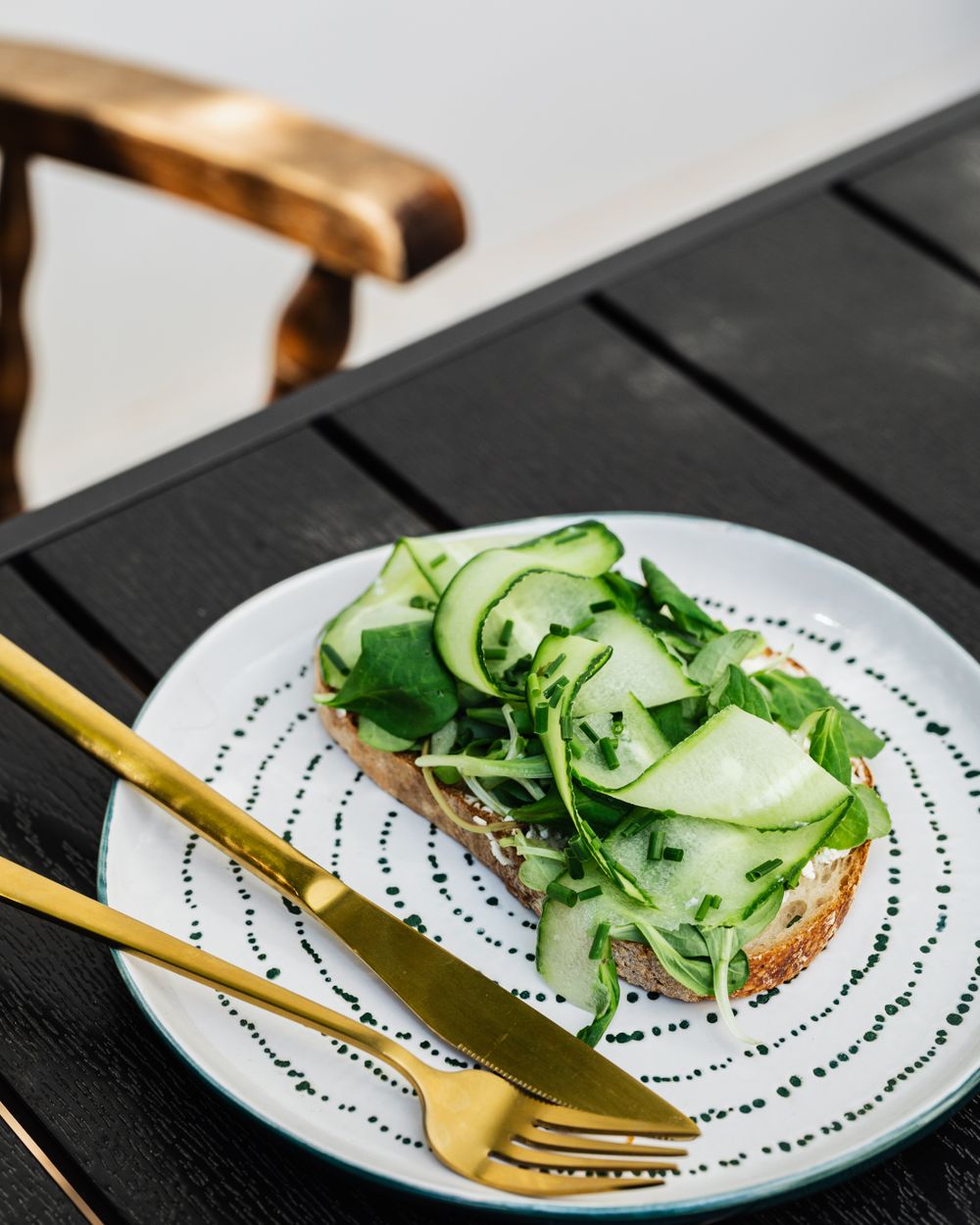 Åben sandwich med agurk og grønt på en mønstret tallerken