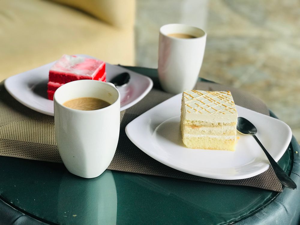 To kopper kaffe og to stykker kage på et rundt bord