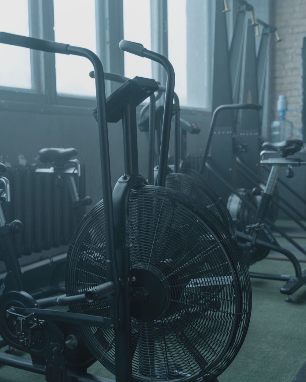 Række af luftcykler ved store vinduer i et mørkt træningslokale